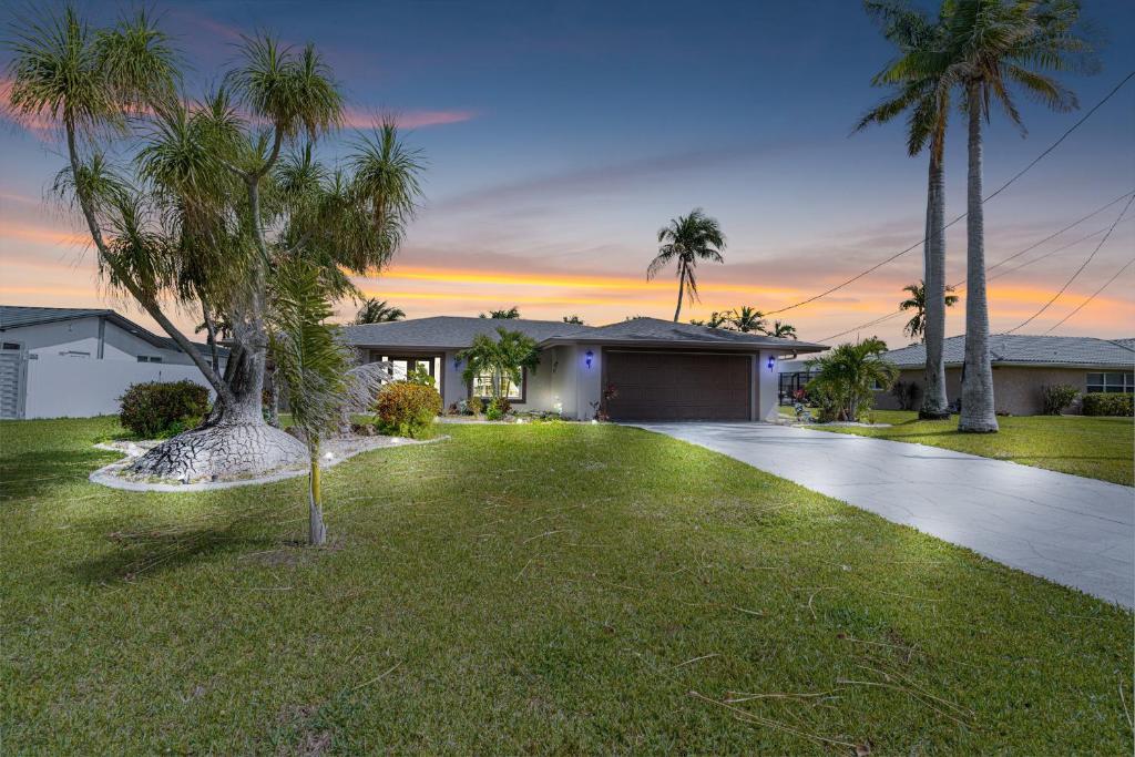 a house with palm trees in front of a driveway at Gulf Breeze Haven Direct Gulf Access Pool+Dock in Cape Coral