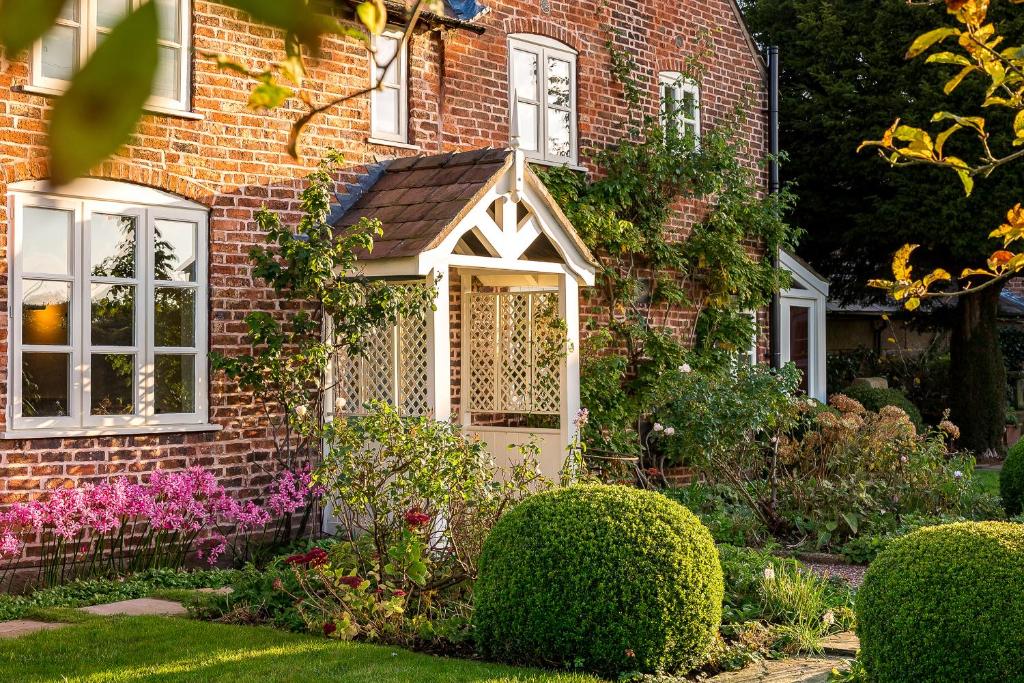 un jardin en face d'une maison en briques dans l'établissement Wheelwrights Cottage, à Tarporley