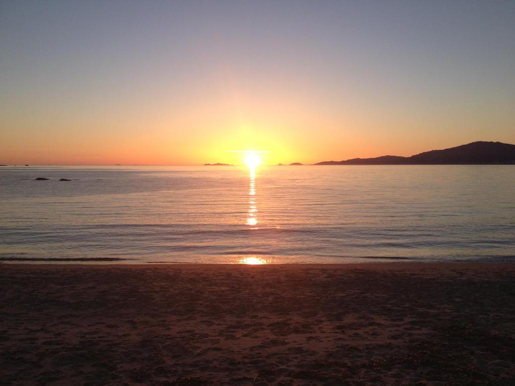 a sunset on the beach with the sun setting at Hotel l'Isolella in Porticcio