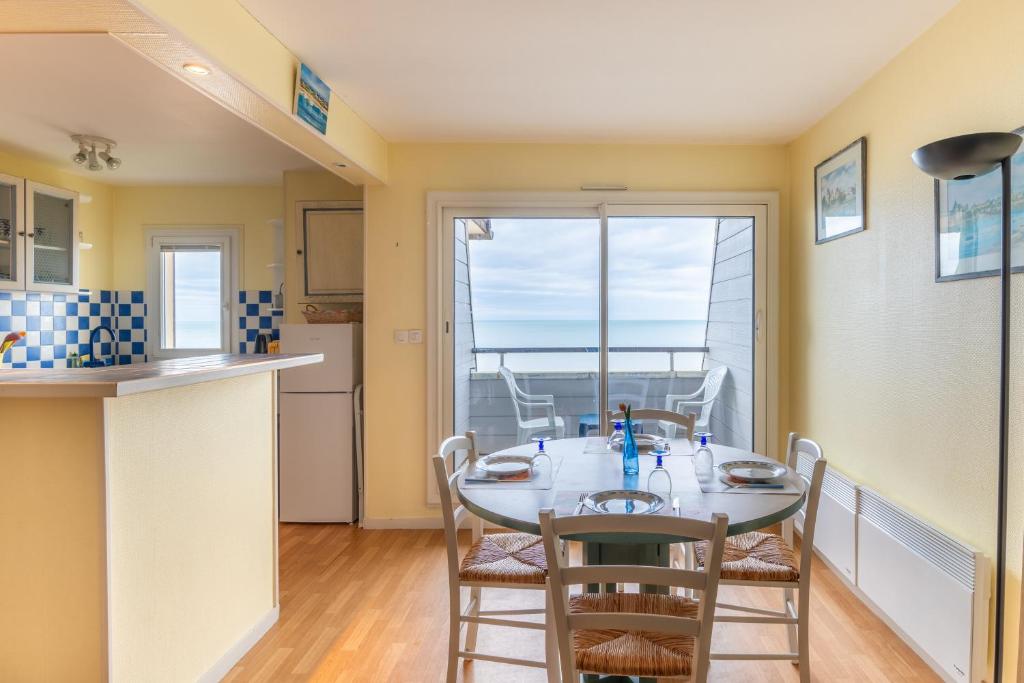 une cuisine et une salle à manger avec une table et des chaises dans l'établissement Le Cap Normand - Vue mer, à Cabourg