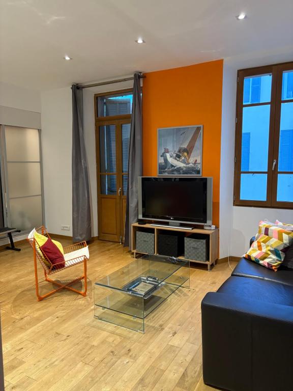 un salon avec un canapé et une télévision à écran plat dans l'établissement Le Léon Noel, à Cannes