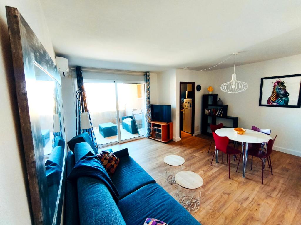 ein Wohnzimmer mit einem blauen Sofa und einem Tisch in der Unterkunft Appartement T2 Bord de Mer - Maria Beach in Santa-Lucia-di-Moriani