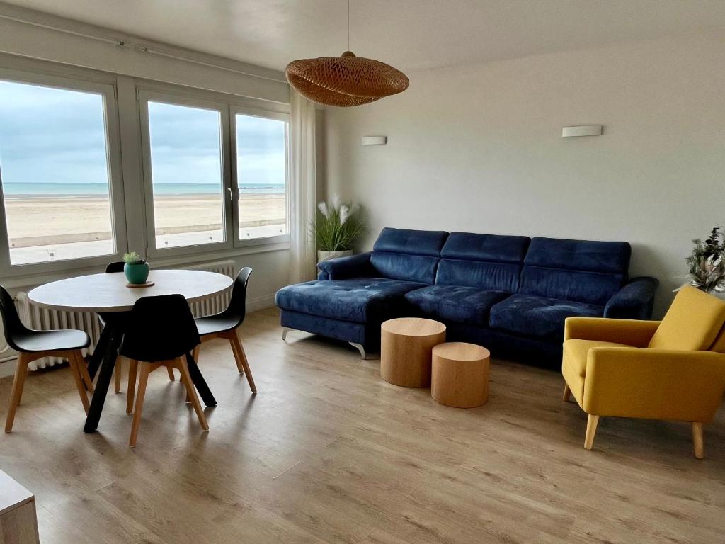 un salon avec un canapé bleu, une table et des chaises dans l'établissement Appartement VUE MER, à Dunkerque