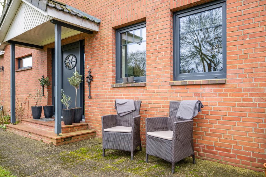 dos sillas sentadas fuera de una casa de ladrillo en Ferienstudio Steensen, en Leck