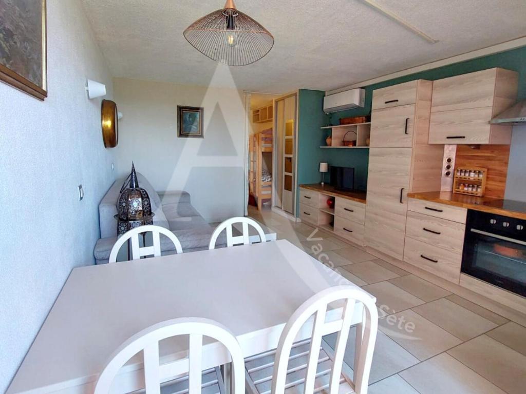 - une cuisine avec une table blanche et des chaises blanches dans l'établissement CAP CORNICHE piscine, studio cabine 4 personnes clim, wifi et parking, à Sète