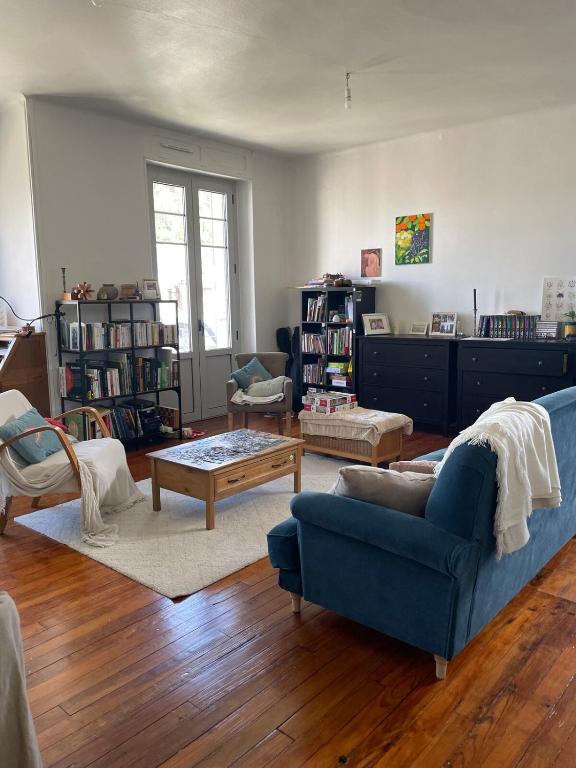 un salon avec un canapé bleu et une table basse dans l'établissement Appartement - Spacieux entre ville et nature !, à Lourdes