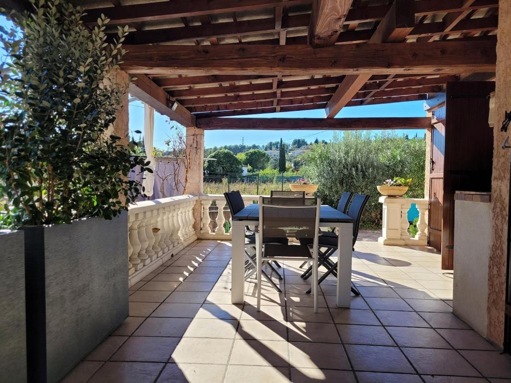 un patio avec une table et des chaises sous une pergola en bois dans l'établissement Coquette maison 3 chambres, climatisée, à Grasse Côte d'Azur, à Grasse