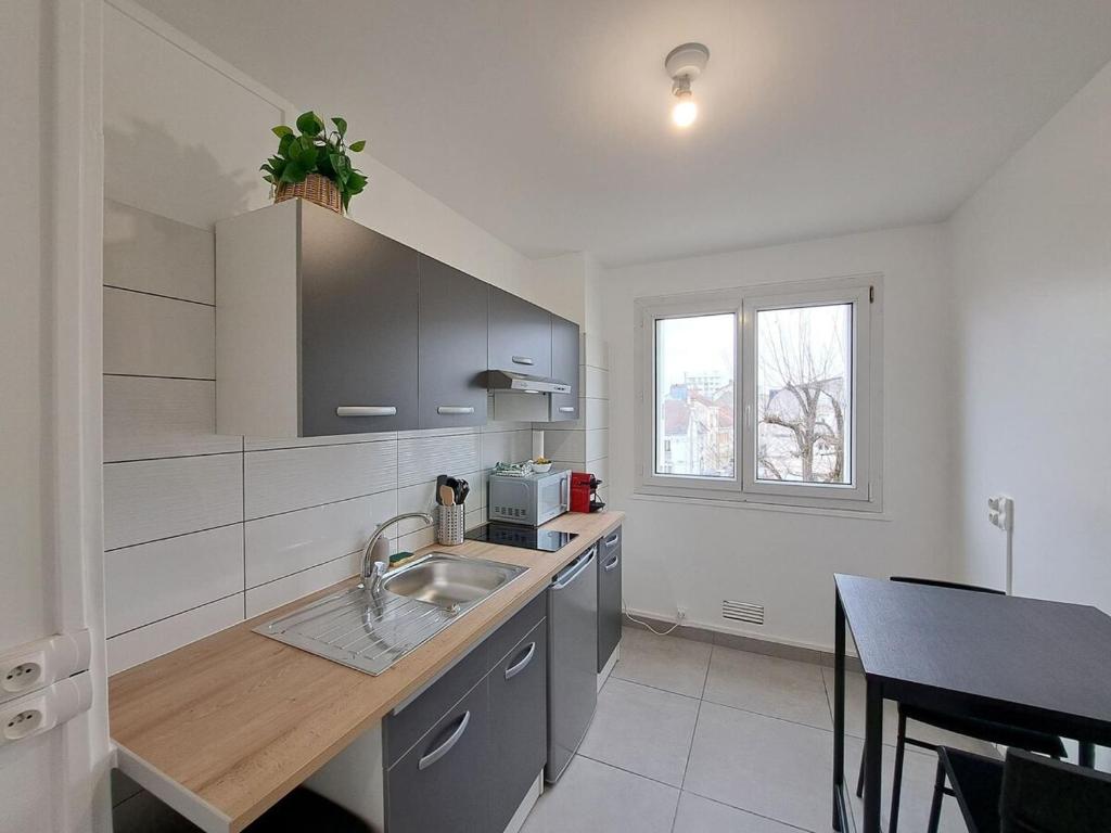 une cuisine avec un évier et une table à l'intérieur dans l'établissement Sofia - Grand appartement, à Reims