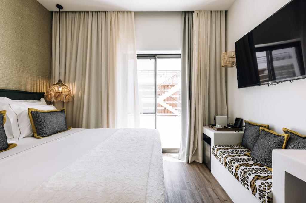 a hotel room with a large white bed and a couch at AlmaLusa Comporta in Comporta