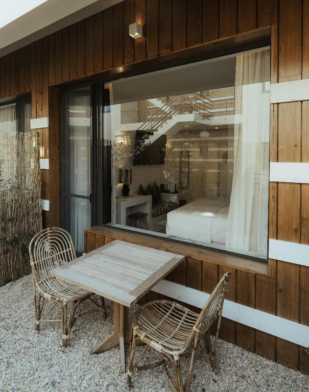 a wooden table and two chairs and a bedroom at AlmaLusa Comporta in Comporta