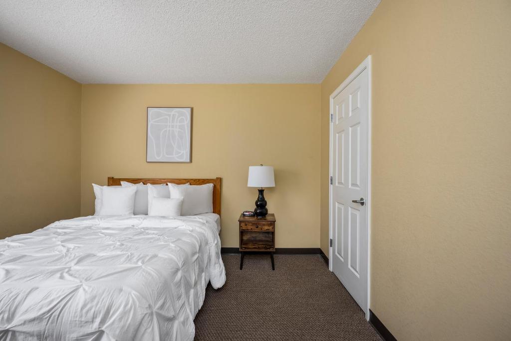 ein Schlafzimmer mit einem Bett, einer Lampe und einer Tür in der Unterkunft Affordable Suites Myrtle Beach in Myrtle Beach