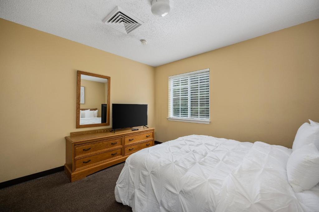 ein Schlafzimmer mit einem Bett und einer Kommode mit Spiegel in der Unterkunft Affordable Suites Myrtle Beach in Myrtle Beach