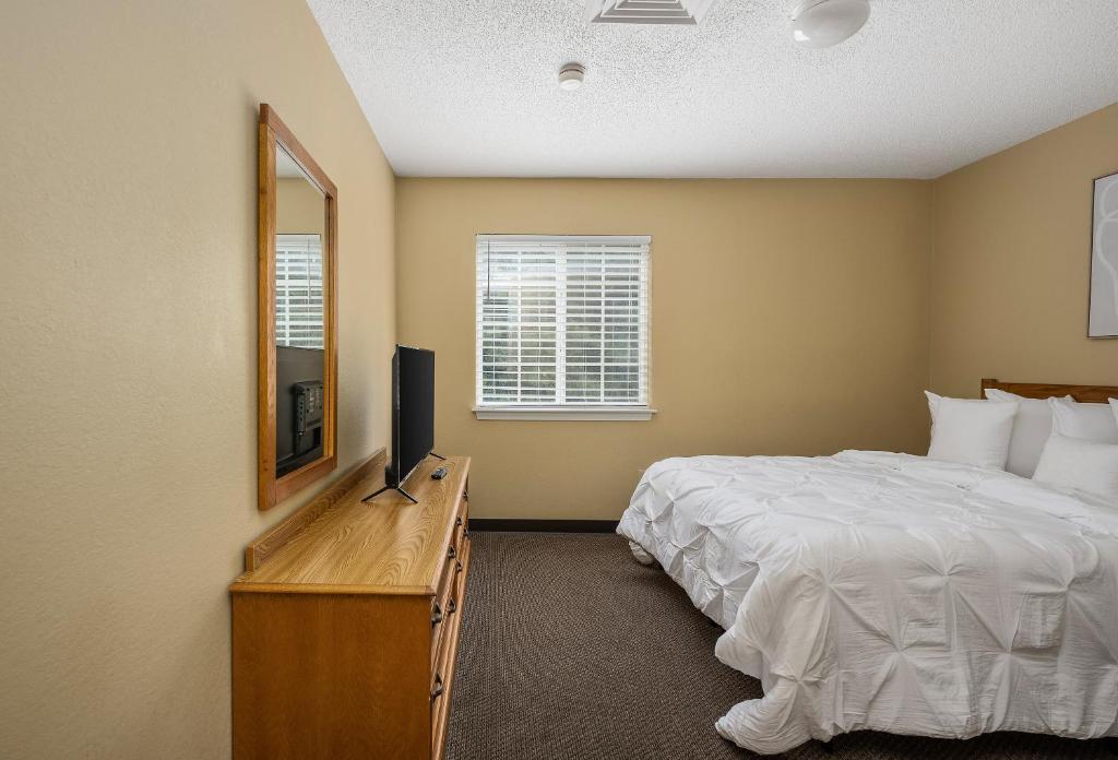 ein Schlafzimmer mit einem Bett, einem Spiegel und einem Fernseher in der Unterkunft Affordable Suites Myrtle Beach in Myrtle Beach
