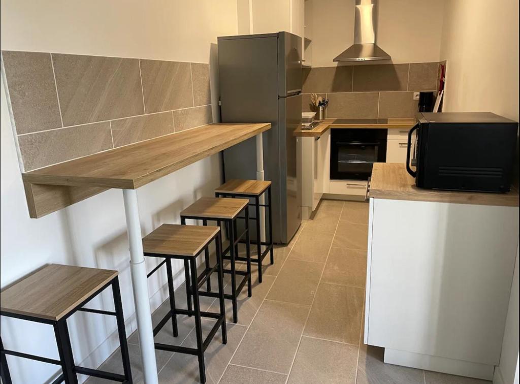 La cuisine est équipée d'un bar avec tabourets et d'un réfrigérateur. dans l'établissement Appartement T2 proche du futuroscope, à Poitiers