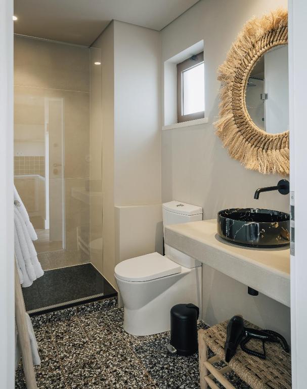 a bathroom with a toilet and a sink and a mirror at AlmaLusa Comporta in Comporta