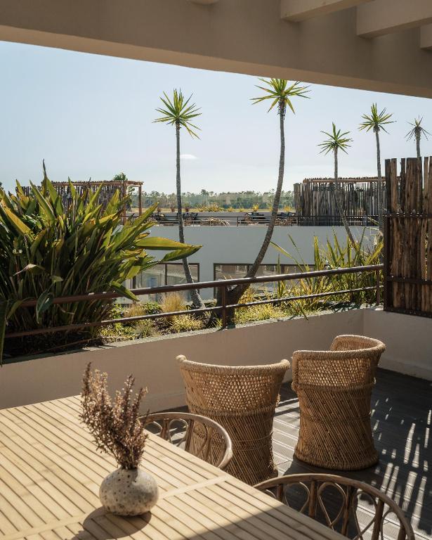 a table and chairs on a balcony with a view of the water at AlmaLusa Comporta in Comporta