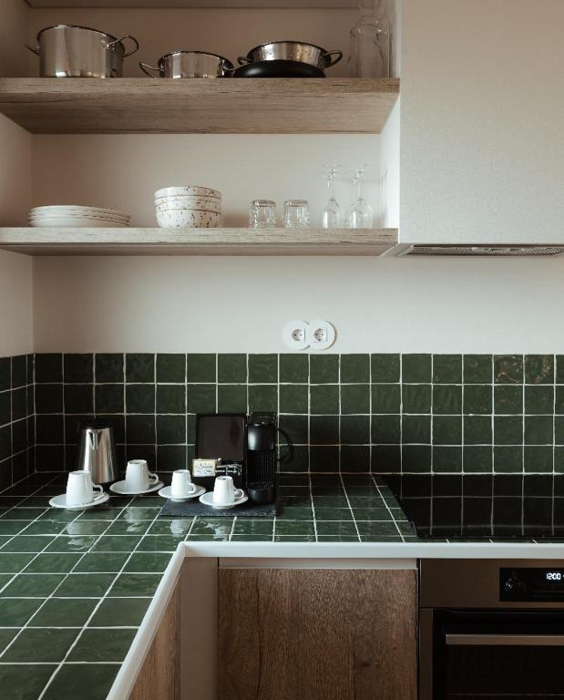 a kitchen with green tiles on the counter top at AlmaLusa Comporta in Comporta