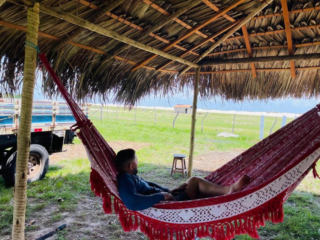 バヘイリーニャスにあるRedário nos Lençois Maranhenses - Canto de Atinsの茅葺き屋根の下に座る男