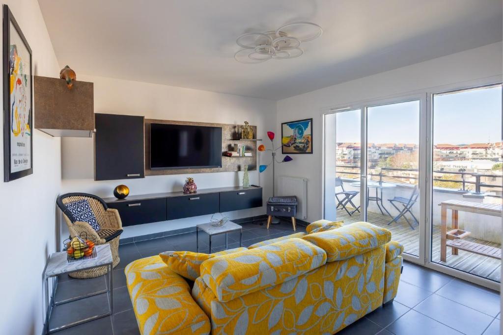 a living room with a couch and a flat screen tv at Atelier Edonya - Au coeur de la Teste in La Teste-de-Buch