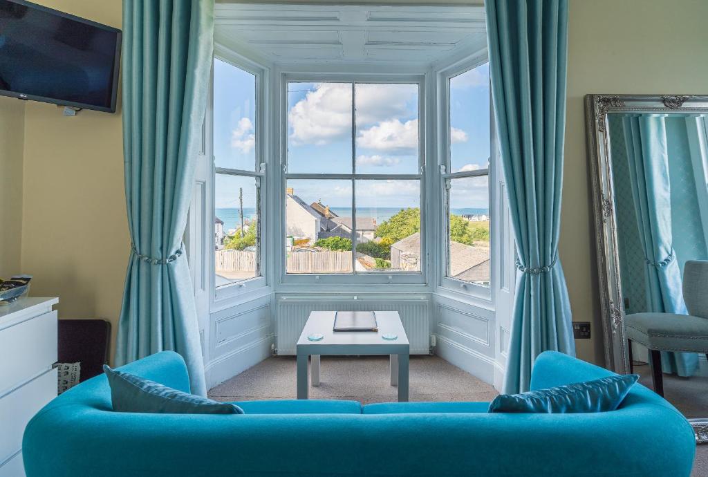 a living room with a blue couch and a large window at Rooms at The Highcliffe in Aberporth