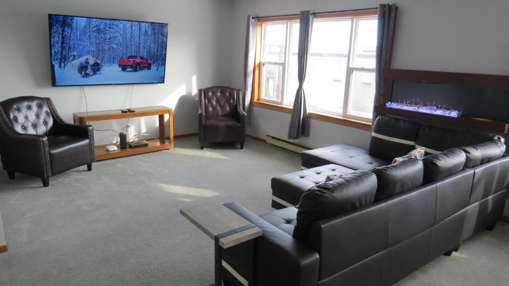 a living room with black leather furniture and a flat screen tv at Dockside Suites in Digby