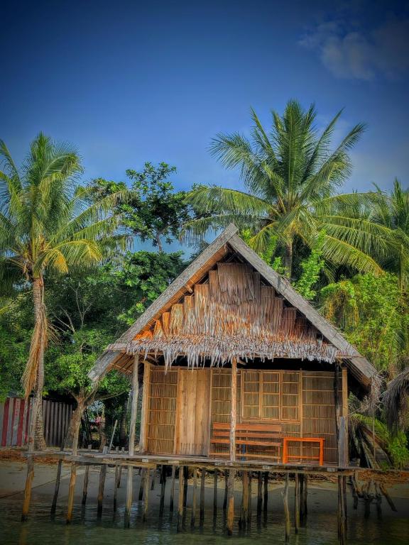 a house on the water with palm trees at Baracuda Homestay in Airborei