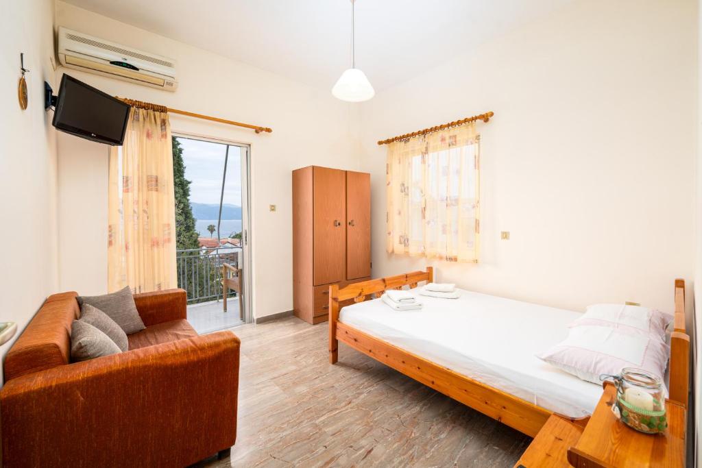 a bedroom with a bed and a couch and a window at Sainis Rooms in Selianitika