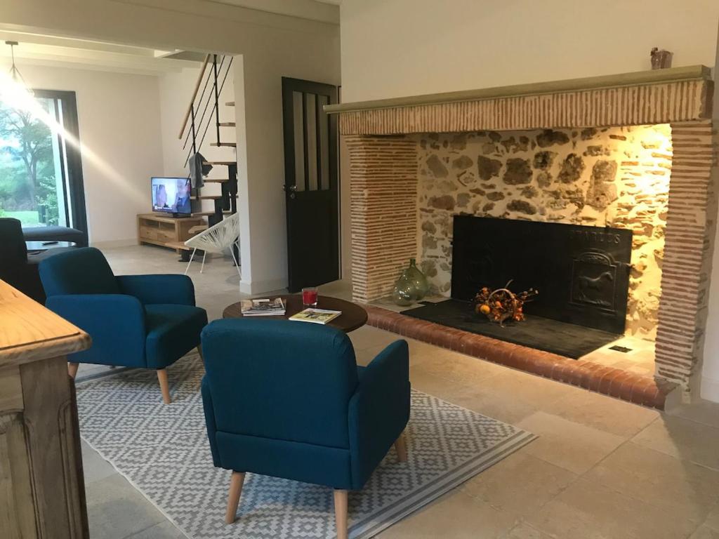 - un salon avec une cheminée et 2 chaises bleues dans l'établissement Gite de FRIZOT, 5 minutes de Nogaro, all inclusiv, à Sion