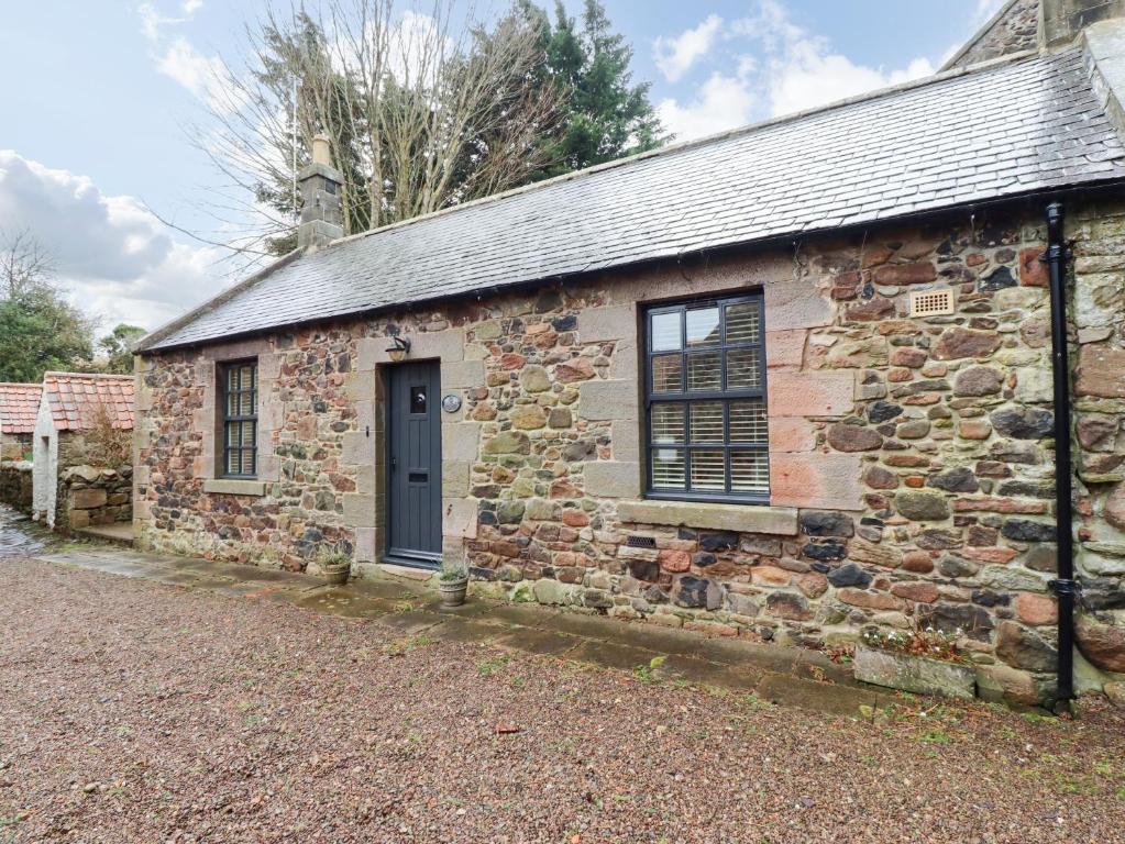 an old stone building with a blue door and windows at Bracken Lodge in Wooler