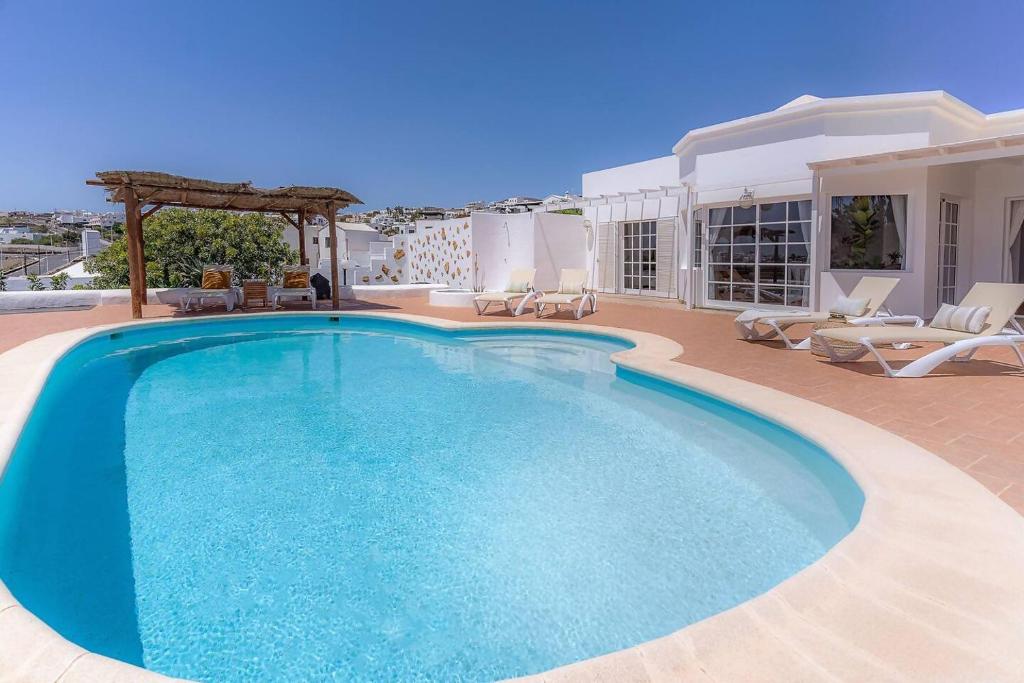 una gran piscina en un patio con sillas en Amazing 3 Bedroom Ocean View with Pool, en Tías
