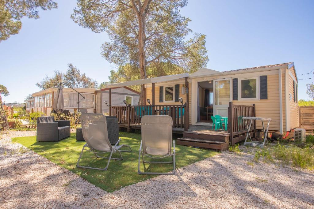 une petite maison avec des chaises et une terrasse dans l'établissement Mobilhome Oasis village Puget, à Puget-sur Argens