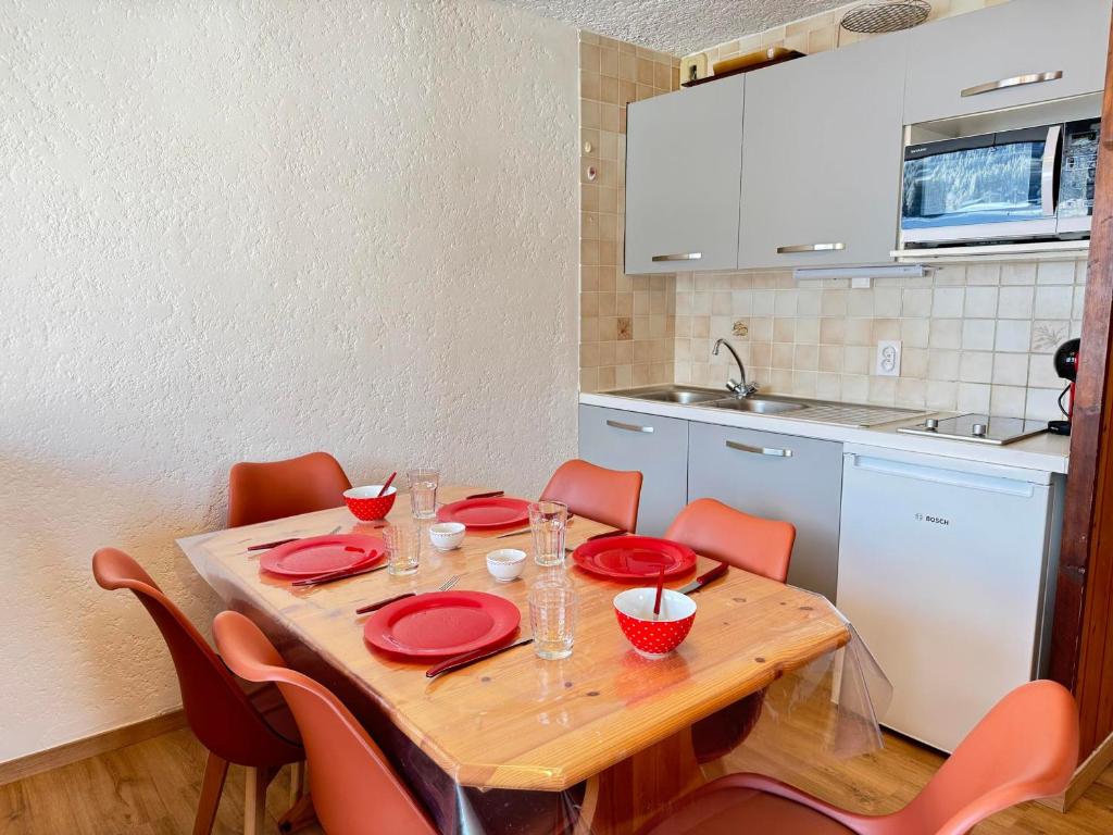 - une cuisine avec une table en bois et des plats rouges dans l'établissement Appartement aux Gets avec vue et animaux acceptés - FR-1-623-143, aux Gets