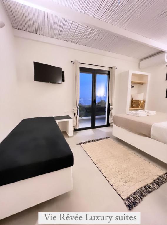 a white bedroom with a bed and a tv at Vie rêvée luxury suites in Ganema