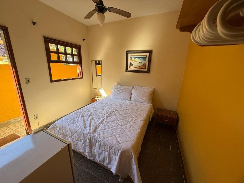 a bedroom with a bed and a ceiling fan at Suites Casa Amarela in Cabo Frio