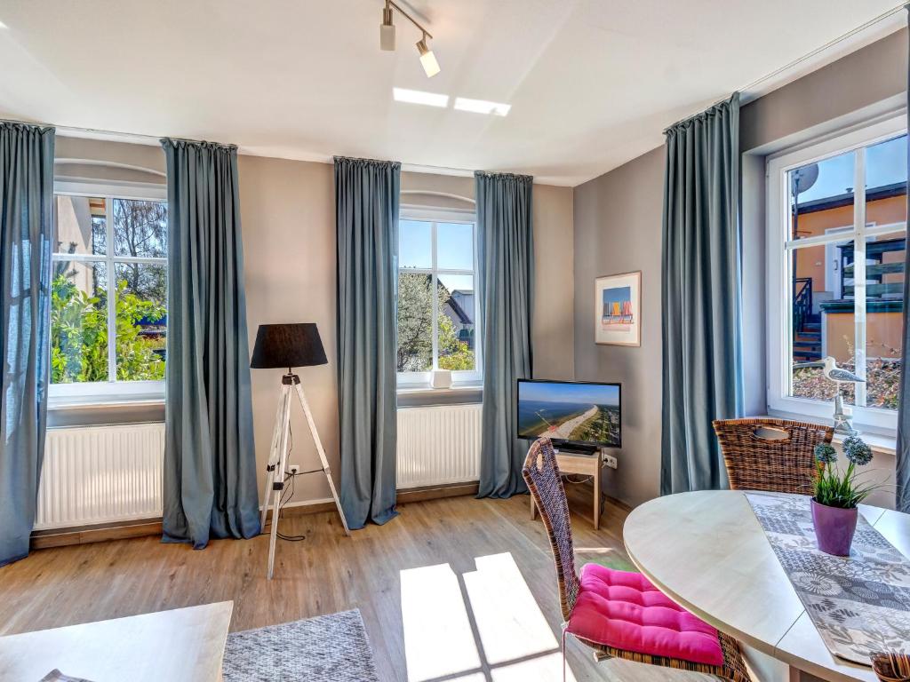 a living room with a table and chairs and windows at Gartenoase Ahlbeck -01 in Ahlbeck