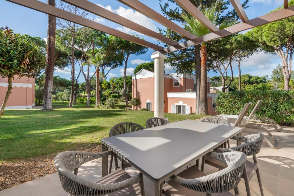 a table and chairs on a patio with trees at Vilar do Golf in Quinta do Lago