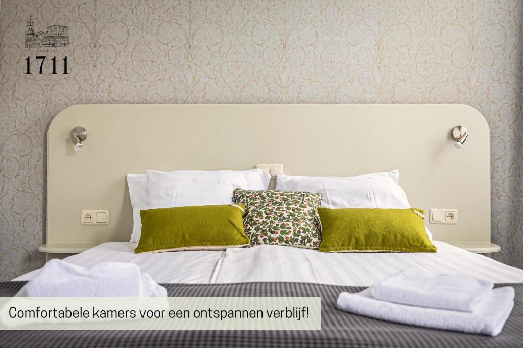 ein Bett mit weißen Laken und grünen Kissen in der Unterkunft Hotel 1711 in Valkenburg