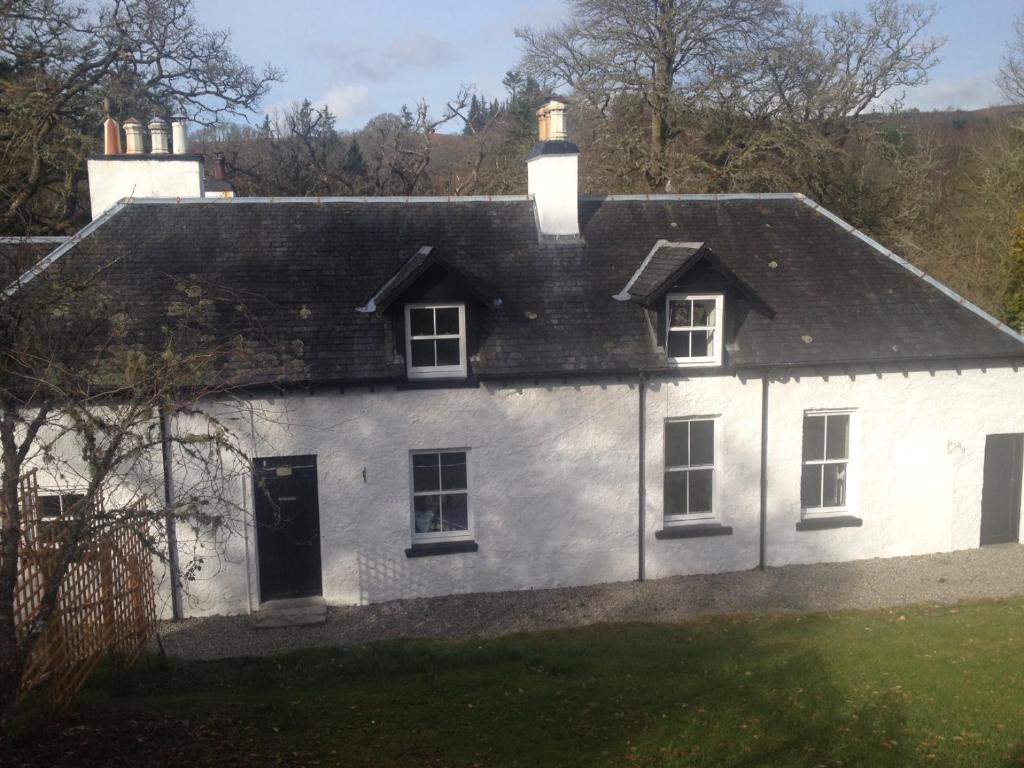 een wit huis met een zwart dak bij The Old Laundry at Allt A'Mhuilinn in Spean Bridge
