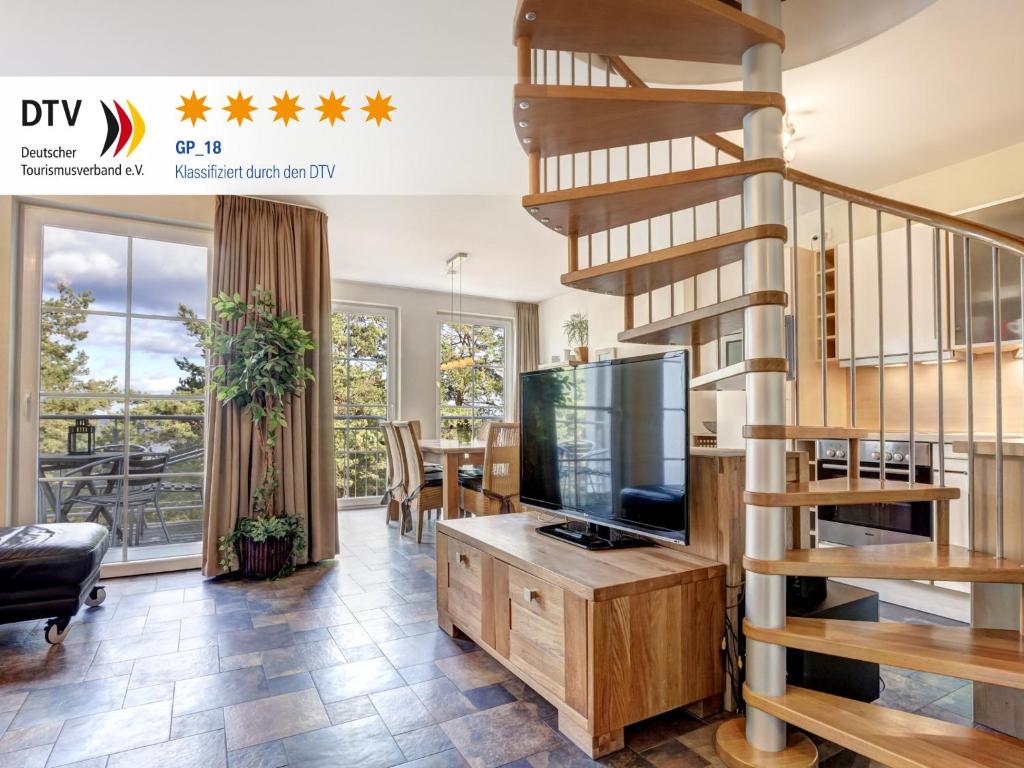 a living room with a tv and a spiral staircase at Ostseeresidenz Gorki- Park - 18 mit Wellness und Schwimmbad in Bansin