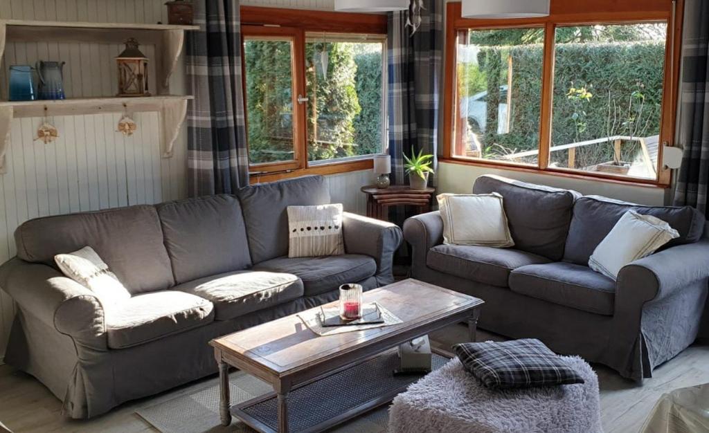 a living room with two couches and a coffee table at Confortable chalet au calme à l'étang du stock in Langatte