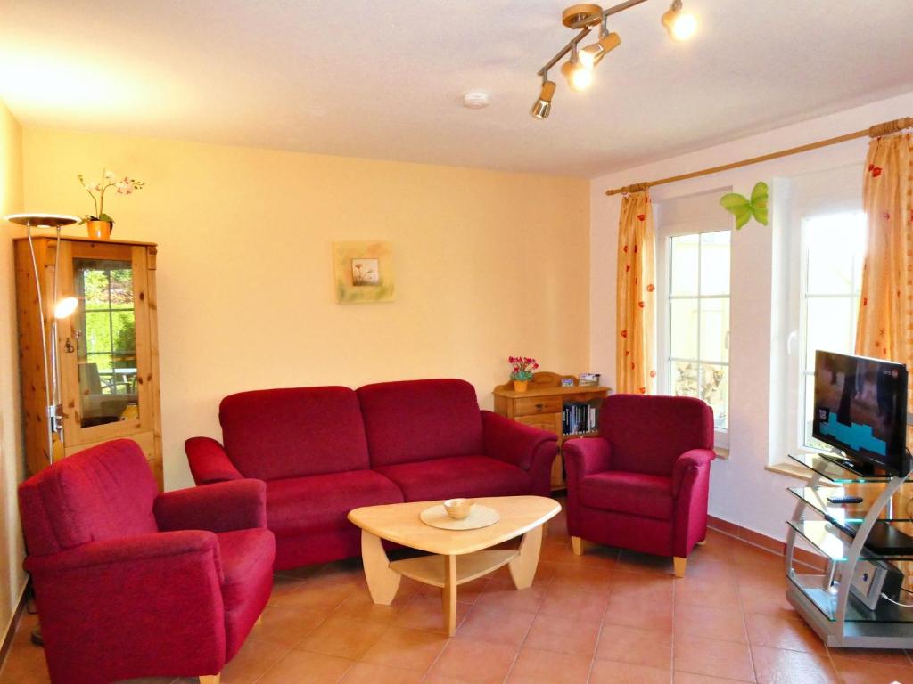 een woonkamer met twee rode banken en een tafel bij Ferienhaus am Eikboom - DHH2 mit Fasssauna in Ostseebad Karlshagen