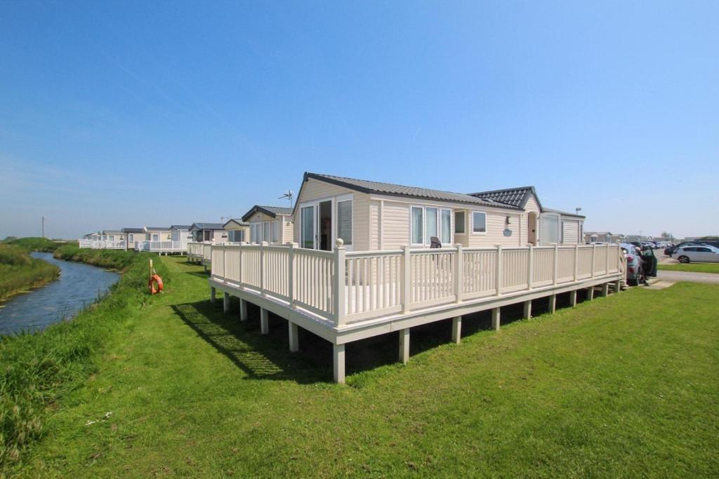 a row of houses on the side of a river at MP261 Parkdean Camber Sands in Camber