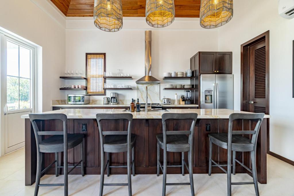 a kitchen with a large island with bar stools at Casa Playa de Denver + Pool Club at Mahogany Bay in San Pedro