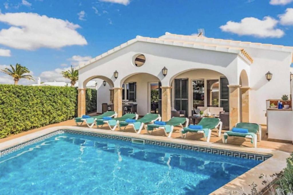 a villa with a swimming pool and chairs at Villa Viola Bosch Menorca in Cala'n Bosch