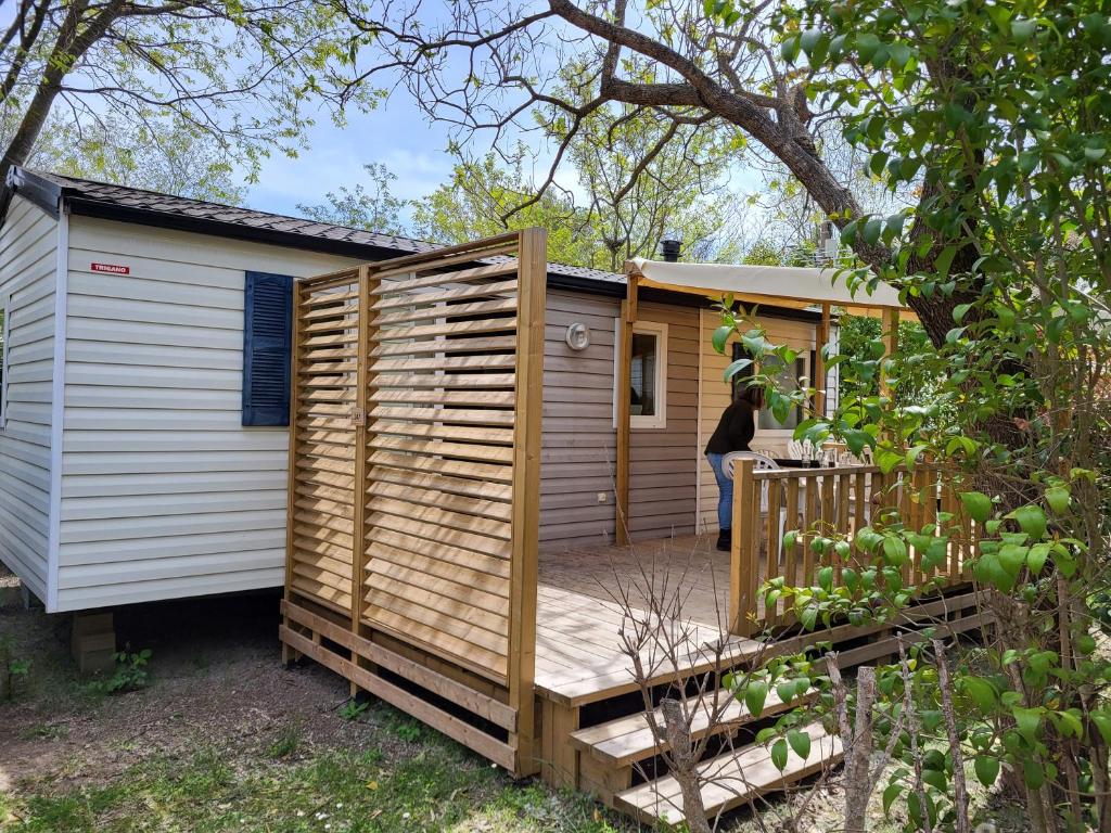 une petite maison avec une grande terrasse en bois dans l'établissement Mobil-home - Le 147 aux Iscles, à La Roque-dʼAnthéron