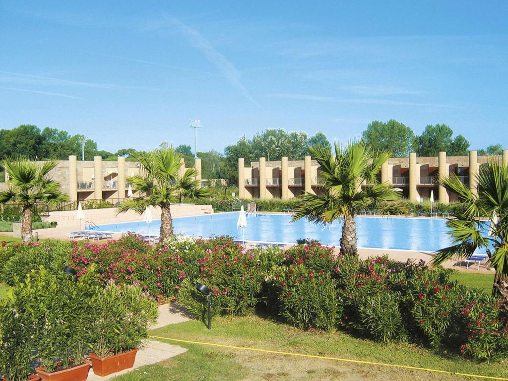 Una gran piscina con palmeras en un complejo turístico. en Apartment Cosmopolitan Golf - TIR280 by Interhome, en Tirrenia