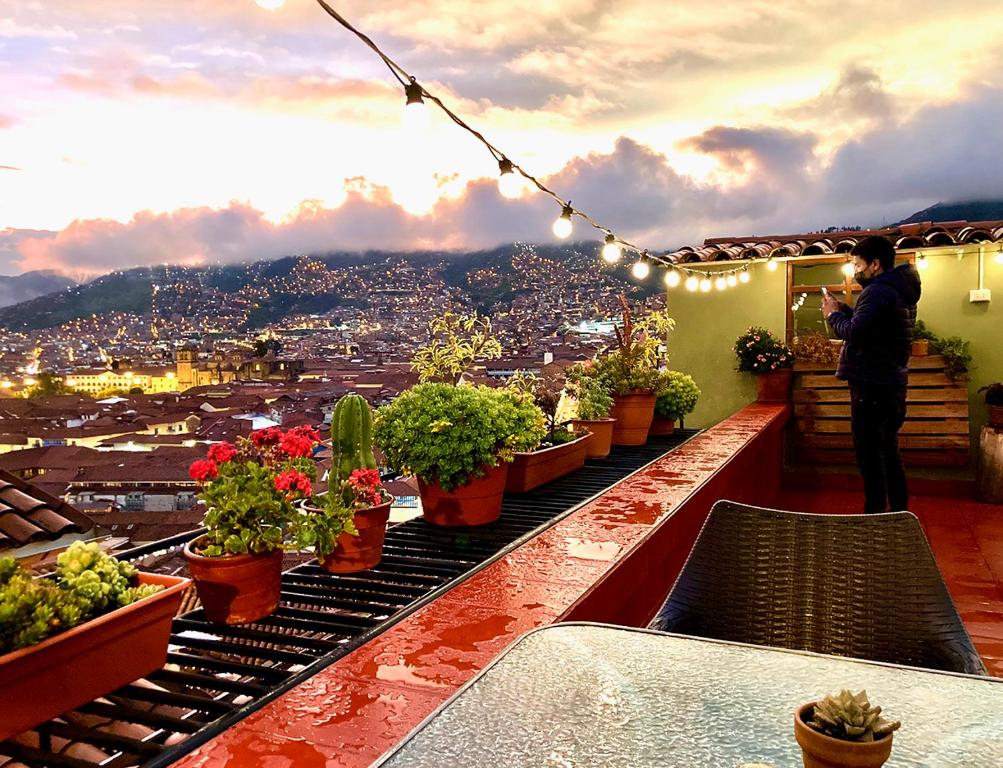 un uomo in piedi su un balcone con piante in vaso di Eco Home View - Guest House a Cuzco