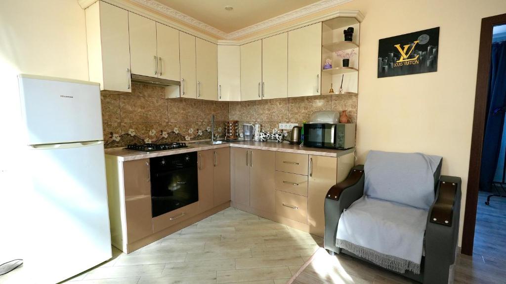 a kitchen with white cabinets and a chair and a refrigerator at SD House in Dilijan