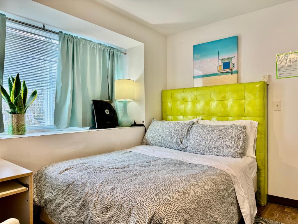a bedroom with a bed with a yellow headboard and a window at Micro Studio Apartment 10 Minutes Walk to University of Washington in Seattle