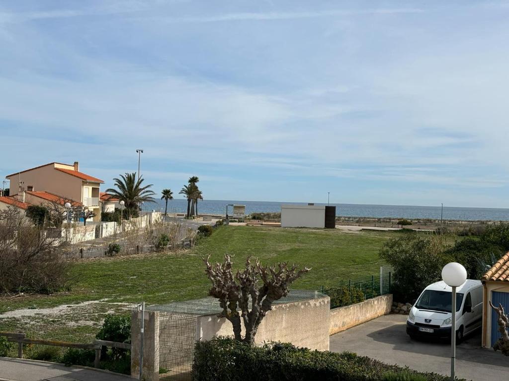 une voiture blanche garée dans une allée près de l'océan dans l'établissement Joli appartement au village du Barcarès, au Barcarès